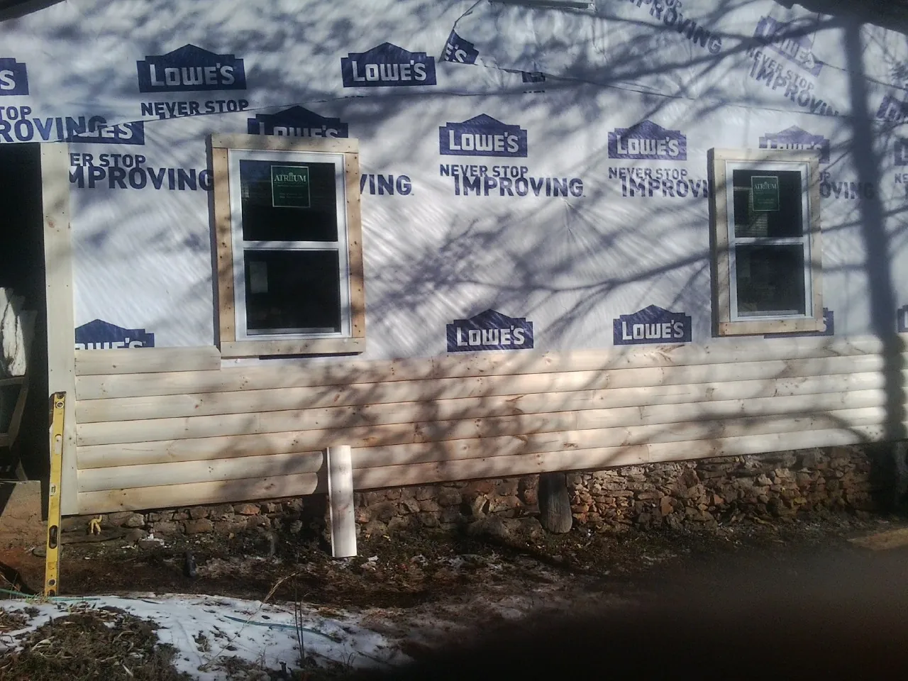 House wrap and new log siding going up on an exterior wall in Akron