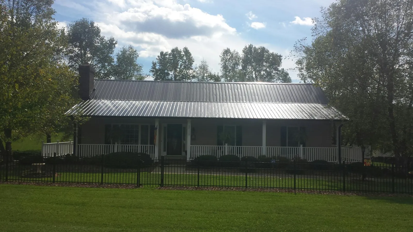 Gray metal roof on a brick ranch with a full width front porch — Gutter Guard Installation work by our crew in Akron