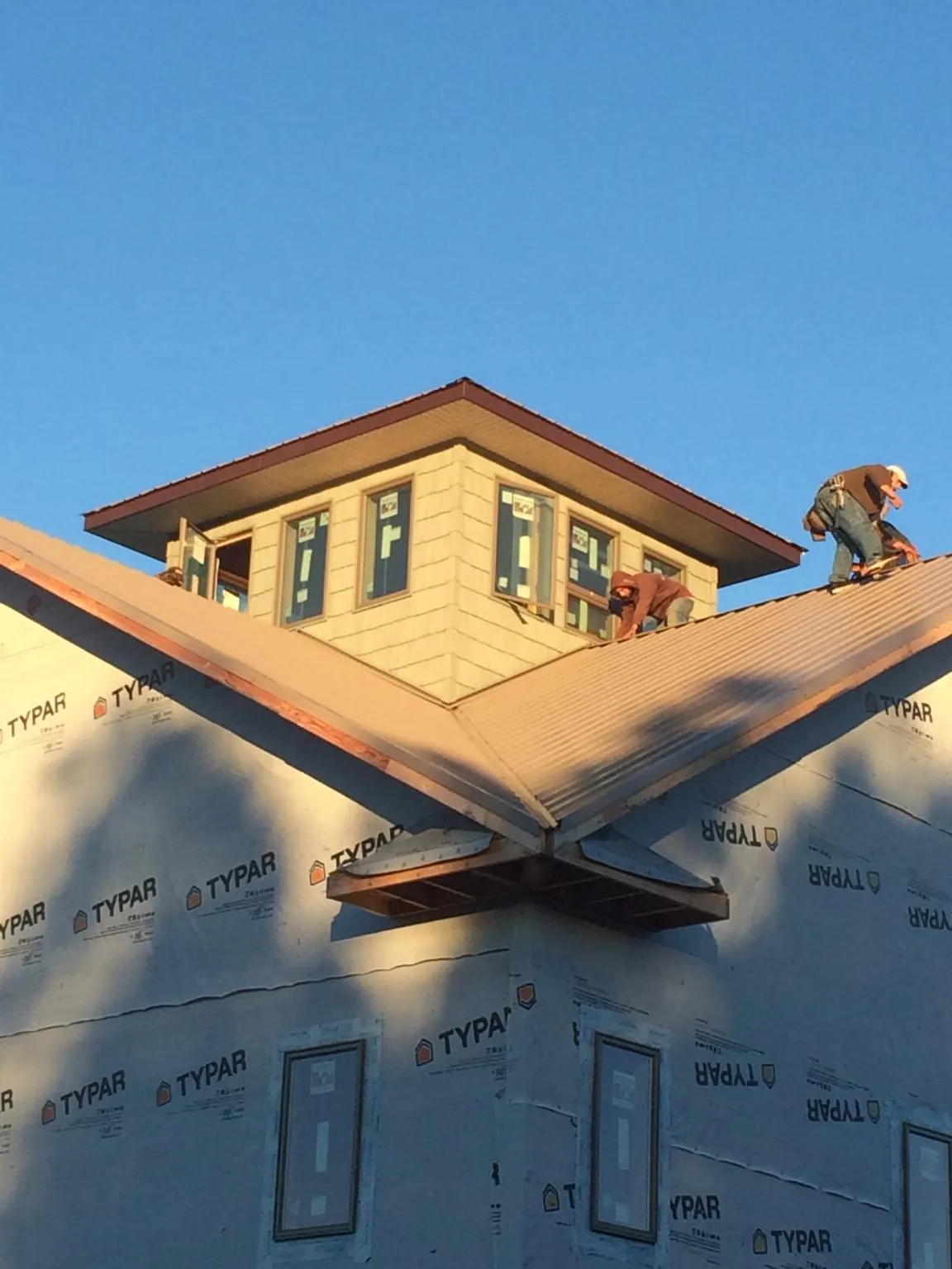 Roofers working around a rooftop cupola on a new metal roof at sunset — Roof Waterproofing in Akron by Roofing Brothers